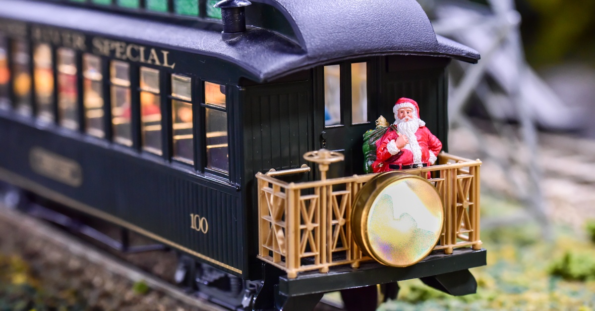 A model toy train setup with a small Santa figurine standing on the back. There are lights on inside the train car.